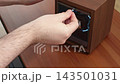 A hand placing a luxury watch into an automatic wooden winder box on a dark brown desk, representing precision maintenance, horology care, and high-end lifestyle product organization 143501031