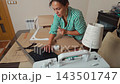 Talented woman sewing and creating patterns in her home workshop studio. 143501747
