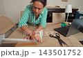 Talented woman sewing and creating patterns in her home workshop studio. 143501752