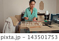 Talented woman sewing and creating patterns in her home workshop studio. 143501753