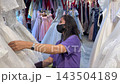 Young asian female customer in protective mask browsing luxury wedding gowns inside bridal showroom shop selecting luxury white dress 143504189