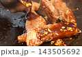 烹飪場景中，一塊豬裡肌肉排在熱板上烤製，淋上蒜蓉醬油，熱氣騰騰，發出滋滋的聲響。 143505692