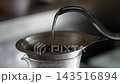 Hand-drip coffee brewing: pouring hot water into a stainless steel dripper, showing the coffee grounds expanding (live-action 4K). 143516894