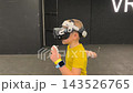 A boy in yellow Tshirt immerses himself in virtual reality. Playing virtual reality game with headset. A party children's center. Modern technology, VR games, and digital entertainment for children. 143526765
