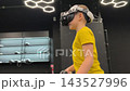 A boy in yellow Tshirt immerses himself in virtual reality. Playing virtual reality game with headset. A party children's center. Modern technology, VR games, and digital entertainment for children. 143527996
