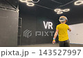 A boy in yellow Tshirt immerses himself in virtual reality. Playing virtual reality game with headset. A party children's center. Modern technology, VR games, and digital entertainment for children. 143527997