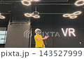A boy in yellow Tshirt immerses himself in virtual reality. Playing virtual reality game with headset. A party children's center. Modern technology, VR games, and digital entertainment for children. 143527999