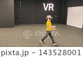 A boy in yellow Tshirt immerses himself in virtual reality. Playing virtual reality game with headset. A party children's center. Modern technology, VR games, and digital entertainment for children. 143528001
