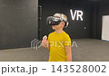 A boy in yellow Tshirt immerses himself in virtual reality. Playing virtual reality game with headset. A party children's center. Modern technology, VR games, and digital entertainment for children. 143528002