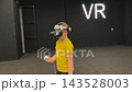 A boy in yellow Tshirt immerses himself in virtual reality. Playing virtual reality game with headset. A party children's center. Modern technology, VR games, and digital entertainment for children. 143528003
