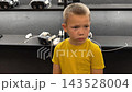 A boy in yellow Tshirt immerses himself in virtual reality. Playing virtual reality game with headset. A party children's center. Modern technology, VR games, and digital entertainment for children. 143528004