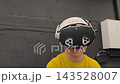 A boy in yellow Tshirt immerses himself in virtual reality. Playing virtual reality game with headset. A party children's center. Modern technology, VR games, and digital entertainment for children. 143528007