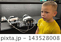 A boy in yellow Tshirt immerses himself in virtual reality. Playing virtual reality game with headset. A party children's center. Modern technology, VR games, and digital entertainment for children. 143528008