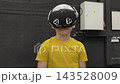A boy in yellow Tshirt immerses himself in virtual reality. Playing virtual reality game with headset. A party children's center. Modern technology, VR games, and digital entertainment for children. 143528009