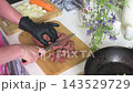 A woman is frying beef liver with onions and carrots in her kitchen. She is preparing a healthy dish that is rich in iron. The kitchen has a simple and clean setup 143529729