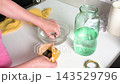In a healthcare setting, a woman carefully moves purchased medicinal leeches from a peat bag into a jar of water. This process prepares the leeches for use in treatment 143529796