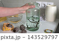 A woman moves purchased medicinal leeches from a bag of peat into a jar of water in a clinic setting. This process is part of hirudotherapy and alternative medicine practices. 143529797