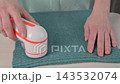 A woman revives the look of her knitted garments with a lint remover. 143532074