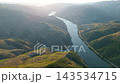 Drone view of the Douro river winding between steep terraced slopes in Portugal Douro Valley, backlit by hazy sunrise light. Push in approach dolly shot. 143534715
