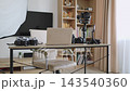 A desk is set up with cameras, a laptop, and lighting equipment for a home photography studio 143540360