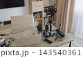 A collection of professional cameras, lenses, and accessories arranged on a wooden desk for content creation 143540361