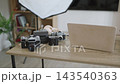 A collection of vintage cameras, a laptop, and lighting equipment are neatly arranged on a wooden desk, ready for a creative session 143540363