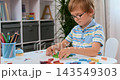 Collage of young boy building with colorful blocks at a table in a bright room 143549303
