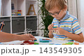 Young boy with glasses doing crafts at table in classroom, collage of video frames 143549305
