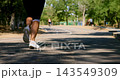 Woman Jogging on Park Path in Sunny Outdoor Setting 143549309