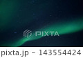 Green aurora borealis ribbon sweeping across starry night sky with soft diffuse glow and tranquil celestial mood, wide diagonal composition from low viewpoint to horizon 143554424