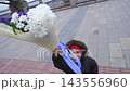 Smiling child holding a large colorful flower bouquet outdoors in the city 143556960