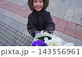 Smiling child holding a large colorful flower bouquet outdoors in the city 143556961