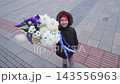 Smiling child holding a large colorful flower bouquet outdoors in the city 143556963