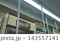 Close view inside a subway train showing metal poles, ceiling lights, and digital destination display. Modern public transport interior with clean design and bright lighting. 143557141