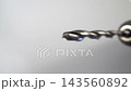 Macro dolly shot of a spinning metal twist drill bit in a power drill chuck slowing to a stop against a clean white studio background in closeup 143560892