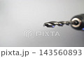 Extreme macro close up of a metal twist drill bit spinning in an electric drill chuck against a soft gray background, dolly shot of rotating steel 143560893