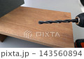 Dolly shot of power drill with metal twist drill bit slowly approaching a wooden board surface in close-up, DIY woodworking and construction concept 143560894