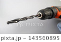 Close-up dolly shot of cordless drill with metal twist drill bit spinning in keyless chuck against gray background, power tool macro detail in studio 143560895