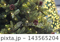 Christmas tree pine branch with pinecone and warm fairy lights bokeh background 143565204