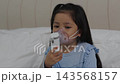 sick preschool child girl using respiratory nebulizer mask in a bed 143568157