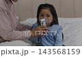 slow motion of mother giving respiratory treatment with nebulizer mask to sick preschool child girl in a bed 143568159