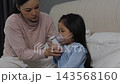 slow motion of mother giving respiratory treatment with nebulizer mask to sick preschool child girl in a bed 143568160