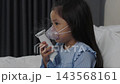 slow motion of sick preschool child girl using respiratory nebulizer mask in a bed 143568161