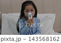 slow motion of sick preschool child girl using respiratory nebulizer mask in a bed 143568162