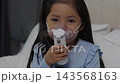 slow motion of sick preschool child girl using respiratory nebulizer mask in a bed 143568163
