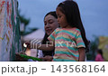 mother and preschool child girl painting watercolors on canvas outdoors in a park 143568164