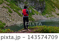 Hiker standing on rocky overlook viewing lake 143574709