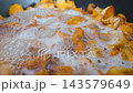 Orange mushrooms boiling in foamy water with bubbles rising around sliced caps and stems during closeup cooking process in dark pan 143579649
