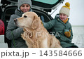 Happy Mother And Daughter With A Dog Rest In A Car Trunk On An Empty Snowy Rural Road 143584666