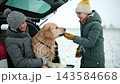 Happy Mother And Daughter Play With Dog And Snow In A Car Trunk At A Winter Road Rest Stop 143584668